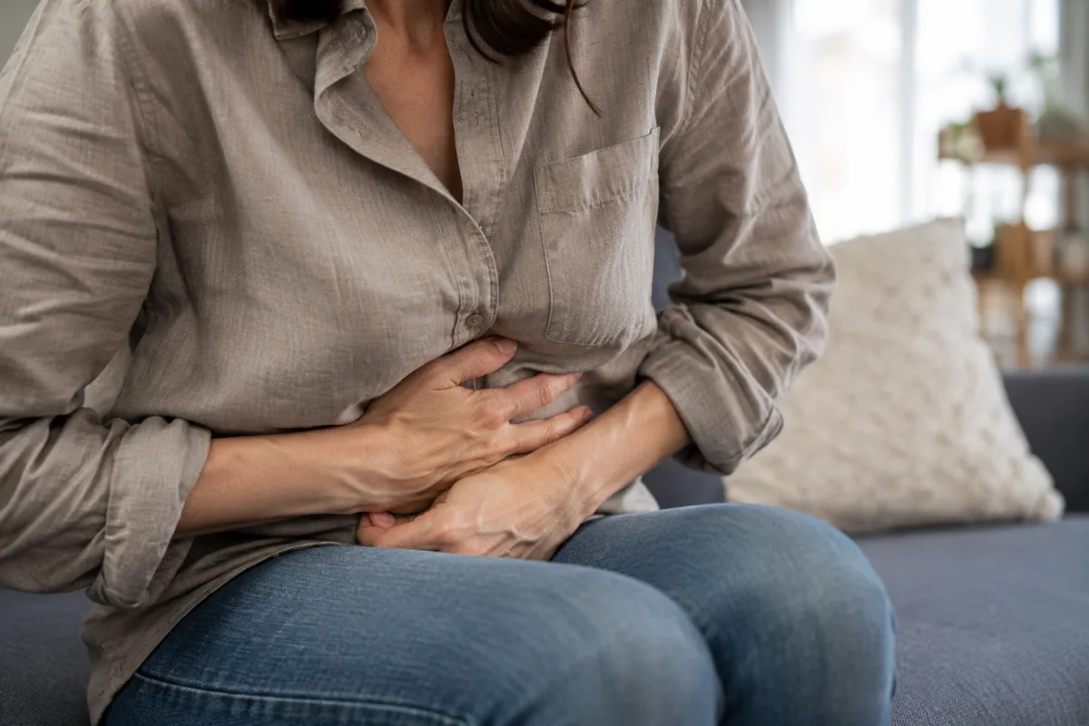 Main posée doucement sur le bas du ventre pour illustrer une gêne abdominale
